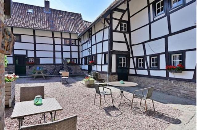 a courtyard with tables and chairs and a building at Vakantiewoningen 'Hoeve de Witte Olifant' in Noorbeek