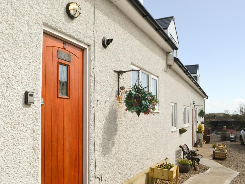 a white building with a red door and a plant at Cygnet Cottage - Uk43546 in Belford