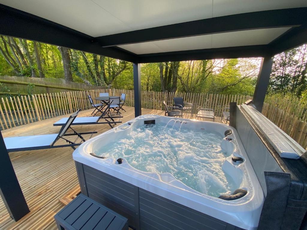 - un bain à remous sur une terrasse avec des chaises et des tables dans l'établissement Domaine du Gros Chêne - terrasses avec jacuzzis privatifs, à Ablon