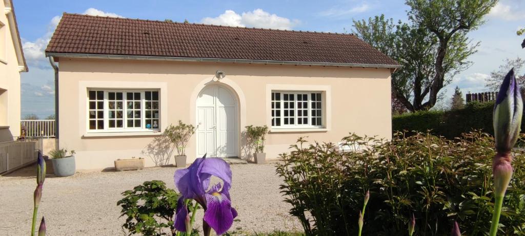 una pequeña casa con una flor púrpura delante de ella en La Petite Maison, en Givry