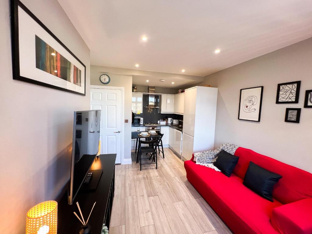 a living room with a red couch and a kitchen at Stylish 2 Bed Apt - Watford Gen Hospital - Watford FC - Professionals & Contractors Welcome in Watford