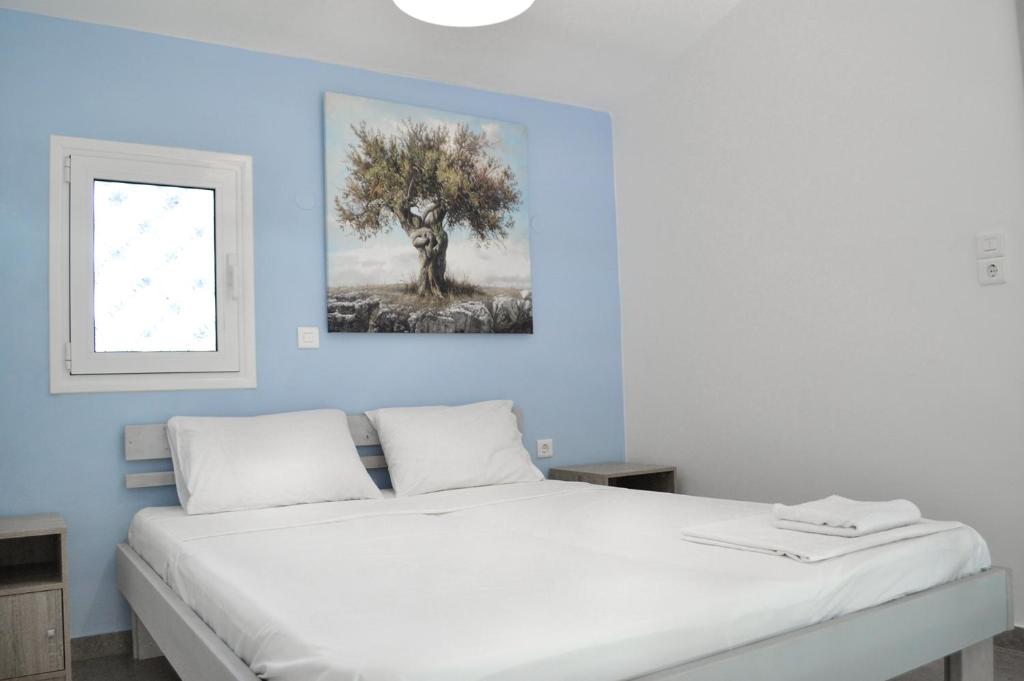 a bedroom with a white bed with a tree painting on the wall at Villa Greco in Vasiliká
