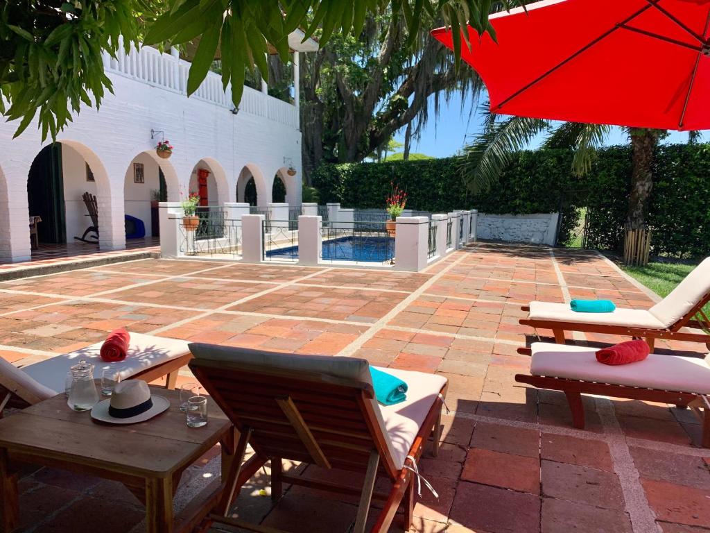 d'une terrasse avec des tables, des chaises et un parasol rouge. dans l'établissement Rancho Saman, à Pereira