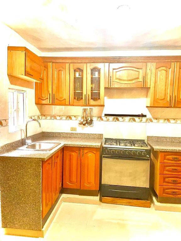 uma cozinha com armários de madeira, um lavatório e um fogão em Buena ventura house em San Luis