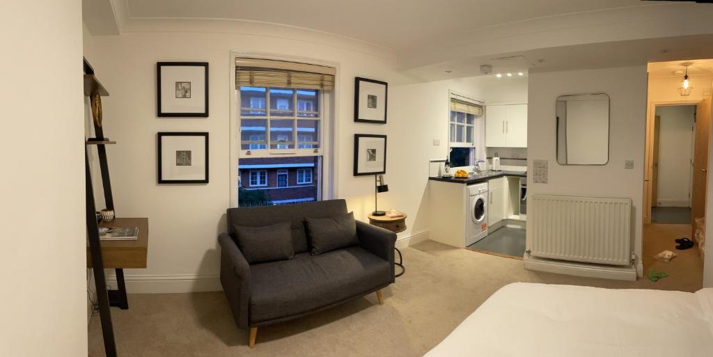 a living room with a chair and a kitchen at Studio flat in the heart of St. Johns Wood in London