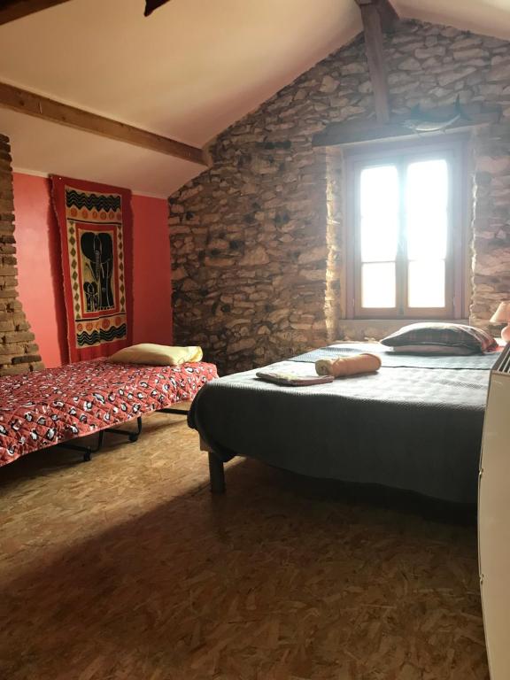 1 dormitorio con 2 camas y pared de piedra en Chambre chez l'habitant Corail cuisine et sdb partagées, en Saint-Sever