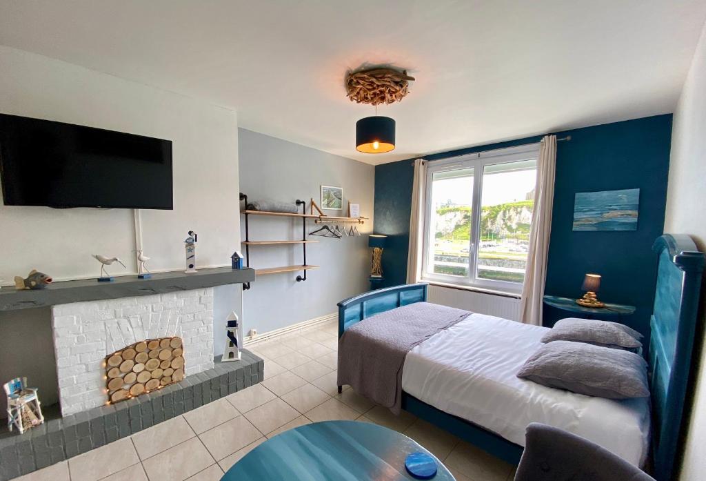 een slaapkamer met een bed, een open haard en een tv bij L’Escapade de Michel - Vue Mer - Élégant in Dieppe