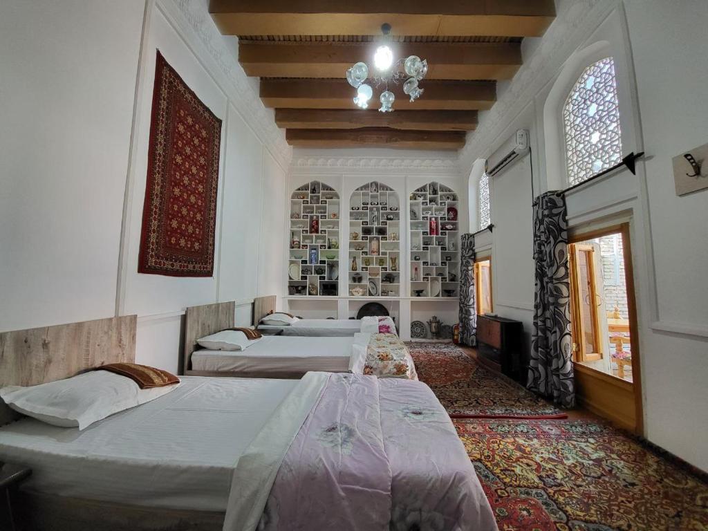 a bedroom with four beds and a chandelier at Bobo Haydar Guest House in Bukhara