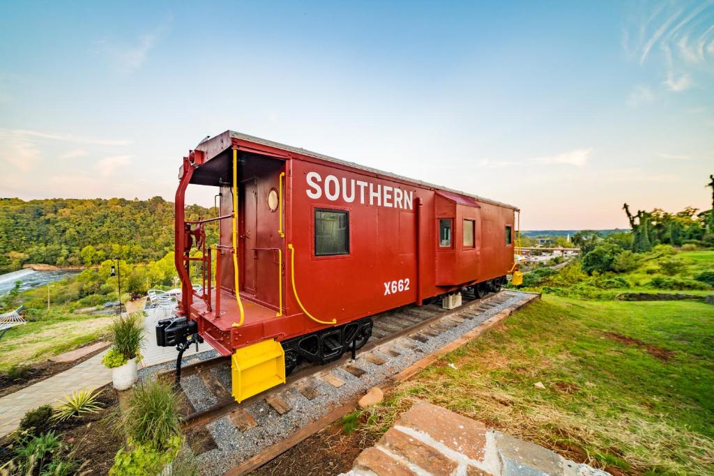 林奇堡James Station Train Caboose with River Views的一辆红色火车车厢坐在轨道上