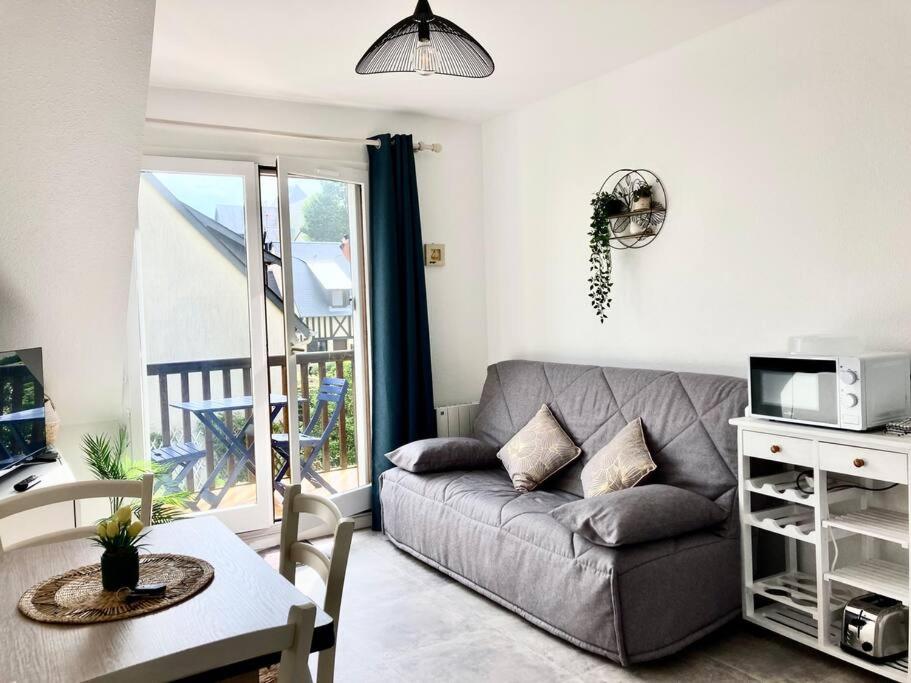 uma sala de estar com um sofá e uma mesa em Cabourg, appartement T2 accès direct mer em Cabourg