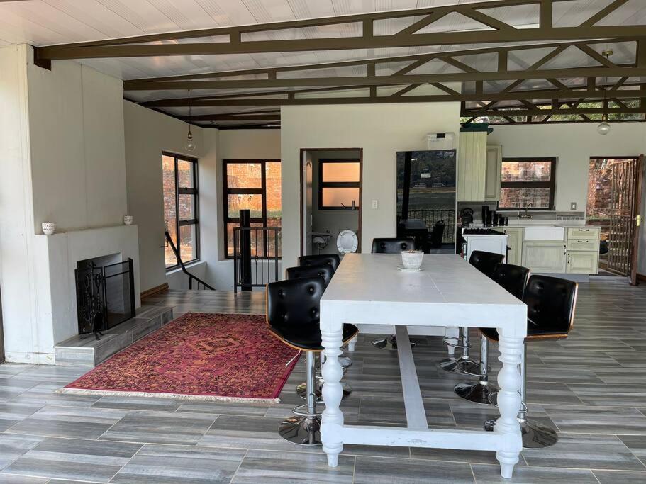 a dining room with a white table and black chairs at Sun Room (Studio) on the edge of the Harties dam. in Hartbeespoort