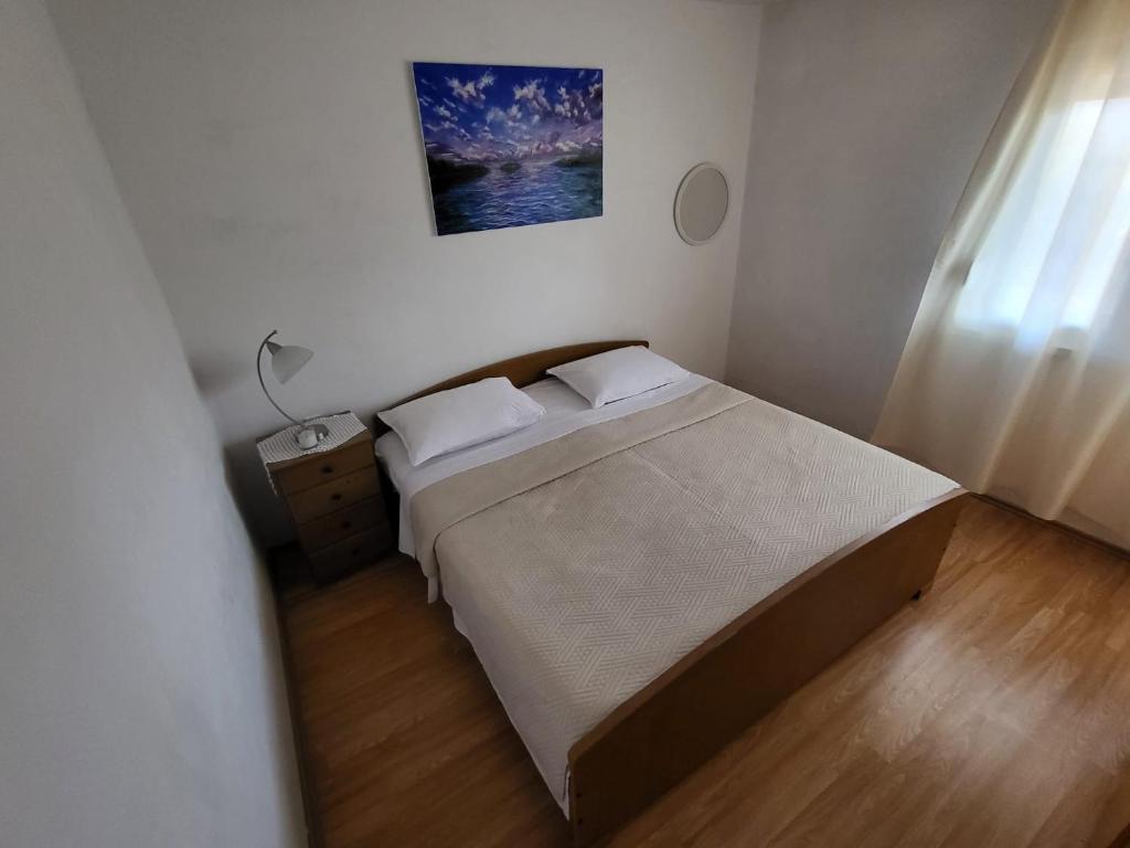 Un dormitorio pequeño con una cama y una lámpara. en Apartman Leona, en Rogoznica