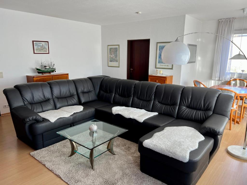 un sofá de cuero negro en una sala de estar con mesa en Lichtdurchflutete große Wohnung en Schwelm