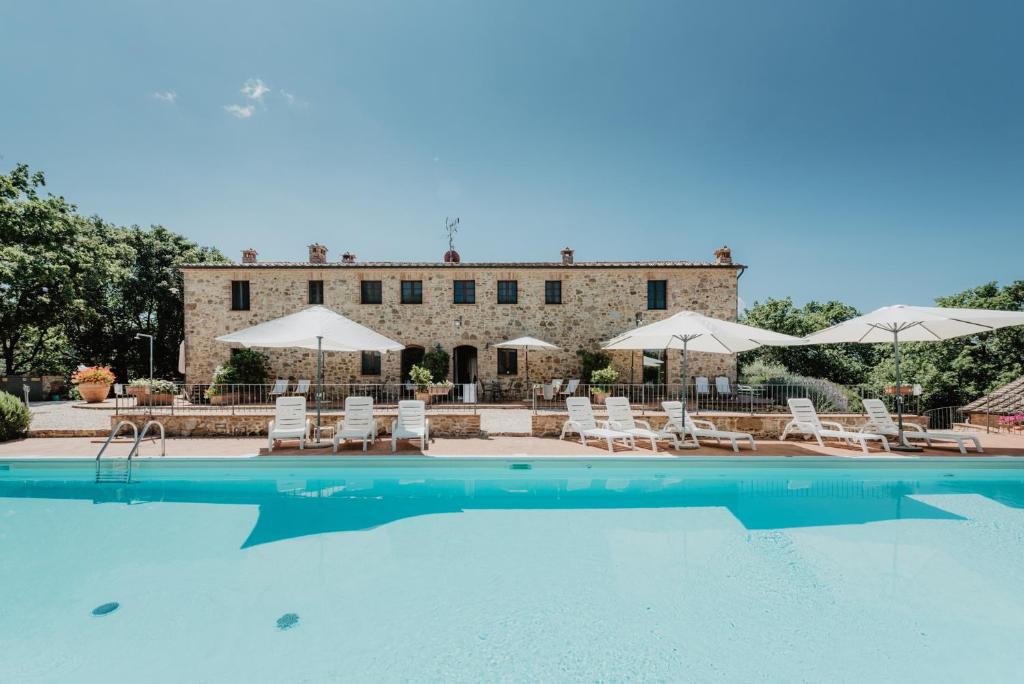 - une piscine avec des chaises et des parasols en face d'un bâtiment dans l'établissement Borghetto Poggio Bianco, à Radicondoli