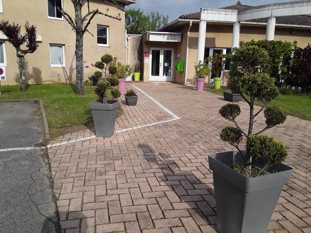 une allée en briques avec des plantes en pot devant un bâtiment dans l'établissement Contact Hôtel ALYS Bourg en Bresse Ekinox Parc Expo, à Bourg-en-Bresse