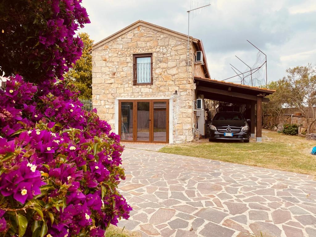 una casa de piedra con un coche aparcado delante de ella en Casa di Pietra, en San Giovanni Suergiu