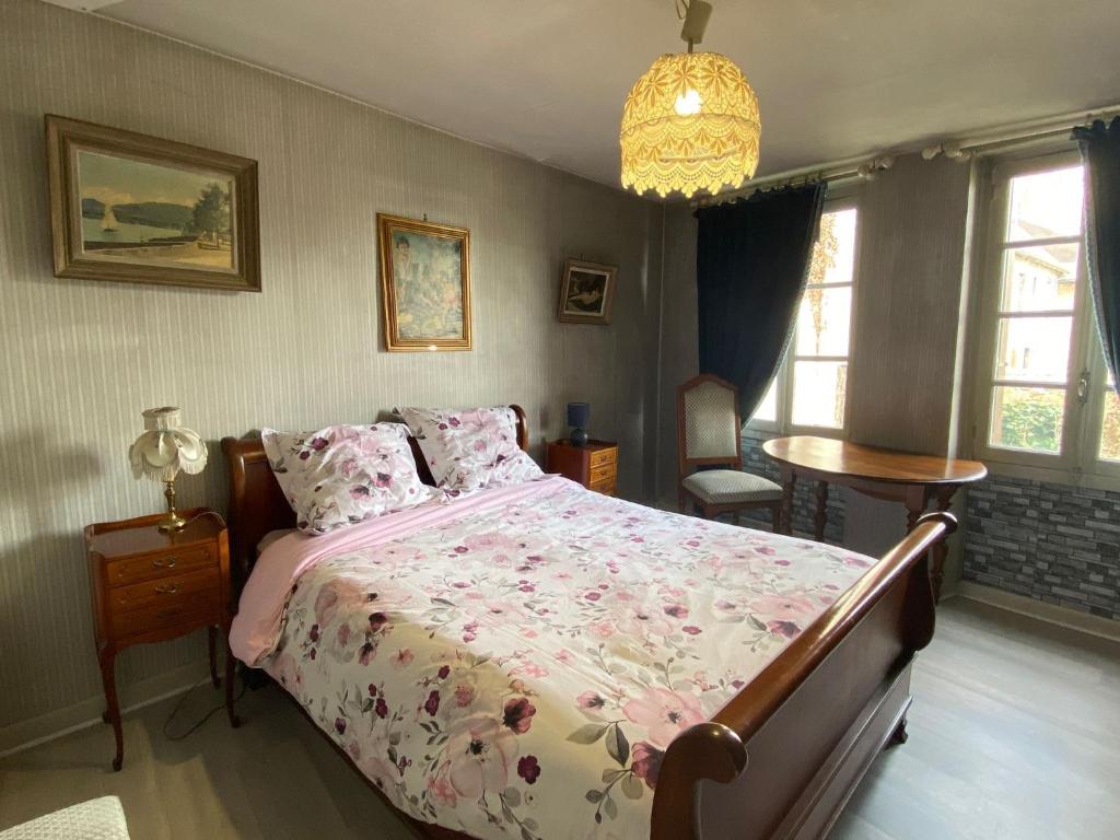 a bedroom with a bed and a table and windows at Chambre calme au cœur d’Ussel in Ussel