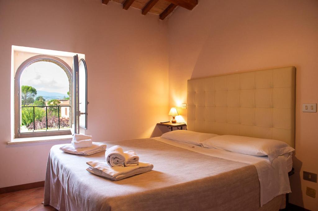 1 dormitorio con 1 cama con toallas y ventana en Torre della Botonta, en Castel Ritaldi