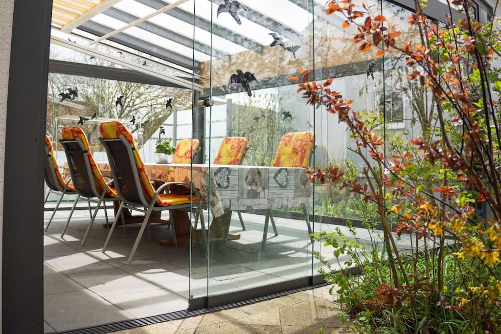 una habitación de cristal con sillas, mesa y algunas plantas en Urlaub mit verglaster Terrasse, en Emmingen-Liptingen