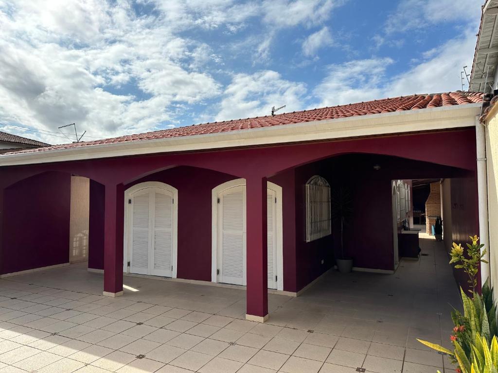 ein lila Gebäude mit weißen Türen und einem Dach in der Unterkunft CASA NO CENTRO DE BERTIOGA in Bertioga