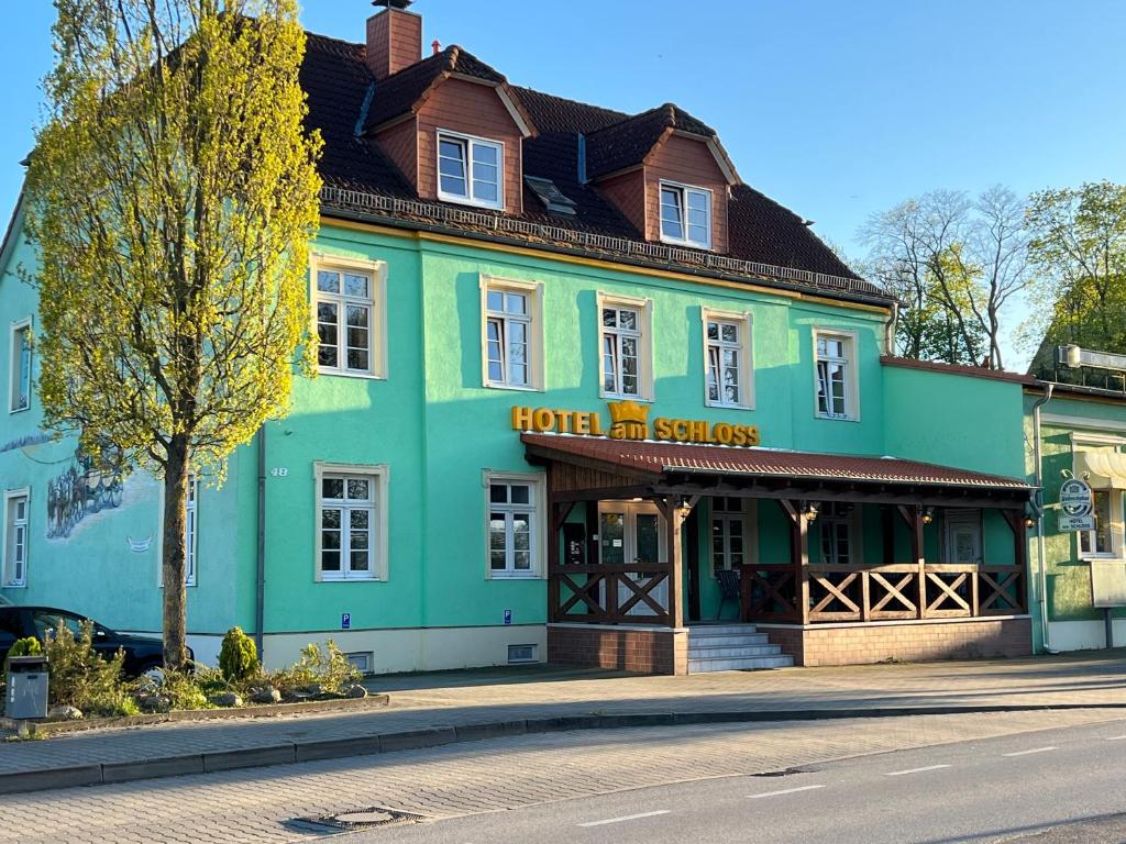 un edificio azul y verde al lado de una calle en Hotel am Schloss - Frankfurt an der Oder, en Frankfurt de Oder