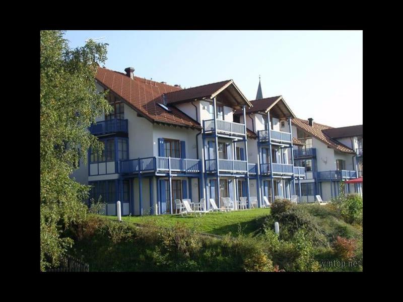 um grande edifício com varandas azuis e cadeiras num campo em Bayern Ferienland Sonnenwald em Schöfweg