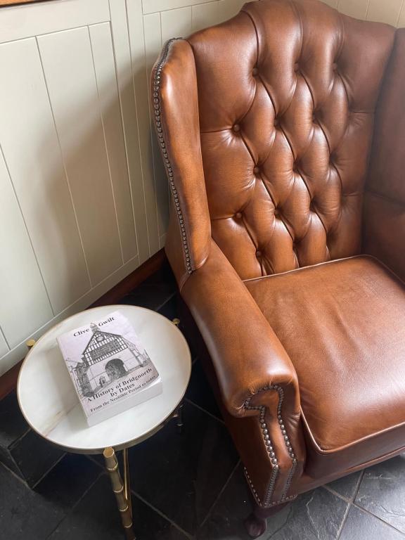 a brown leather chair sitting next to a side table at The Railway Cottage Bridgnorth in Bridgnorth