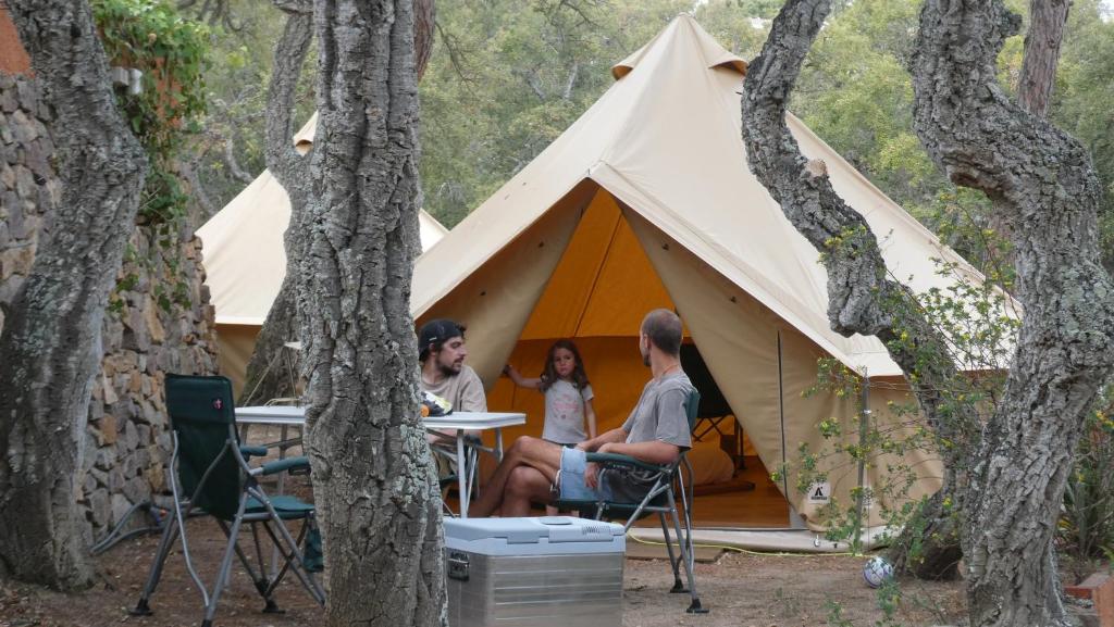 ACAMPALE - Camping Costa Brava - Calella de Palafrugell في كاليلا دو بالافروجيل: مجموعة من الناس يجلسون أمام خيمة