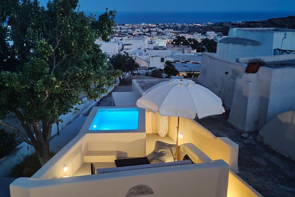 a swimming pool with an umbrella and some chairs at Dreamer's Secret villa 2 in Emporio Santorini