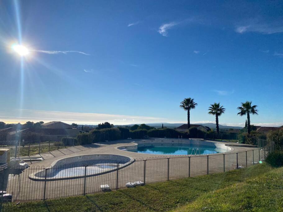 西格的住宿－Duplex 6 pers proche circuit Paul Ricard Le Castellet avec piscine，一座棕榈树和围栏的游泳池