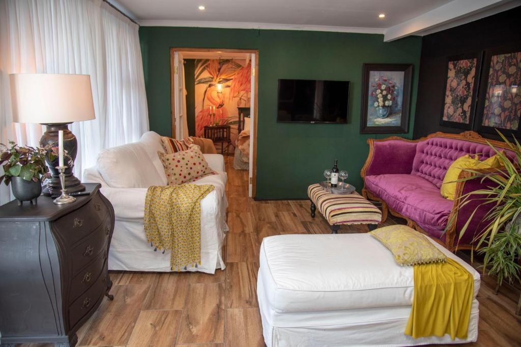 a living room with a purple couch and white chairs at La Lupa Nera in Knysna