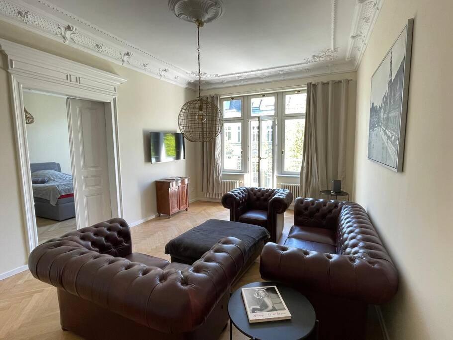 ein Wohnzimmer mit einem Ledersofa und 2 Stühlen in der Unterkunft Ruhige&charmante Altbauwohnung in Leipzig