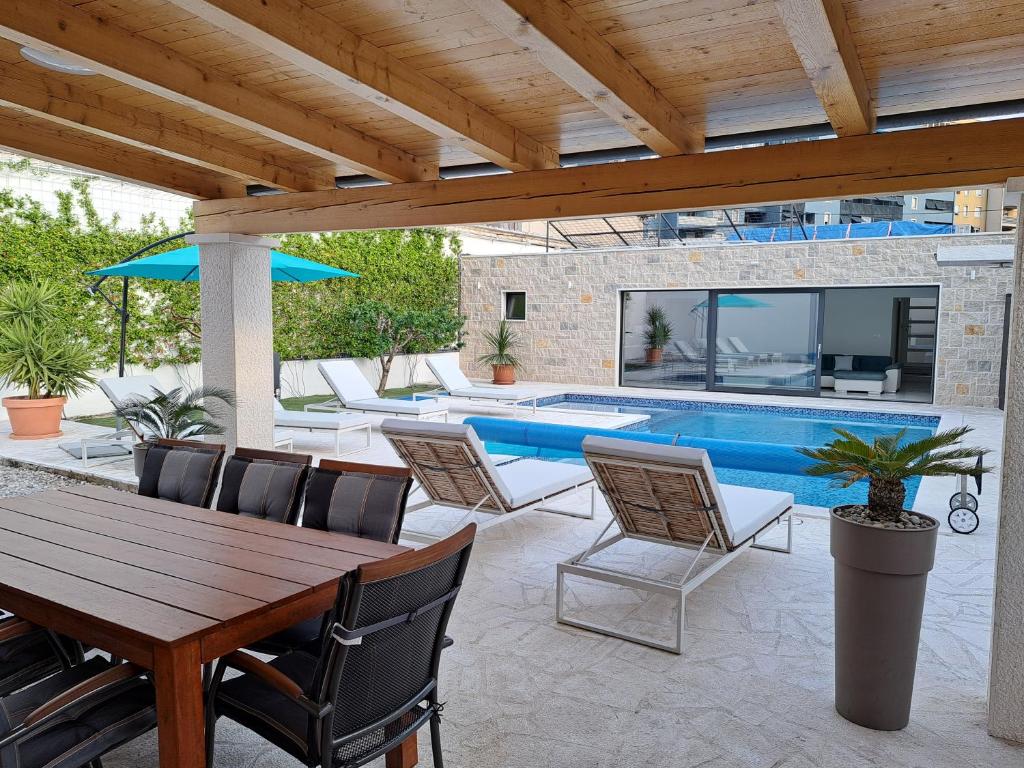 een patio met een tafel en stoelen en een zwembad bij VILLA ENJOY LUX private heated pool in Split in Split