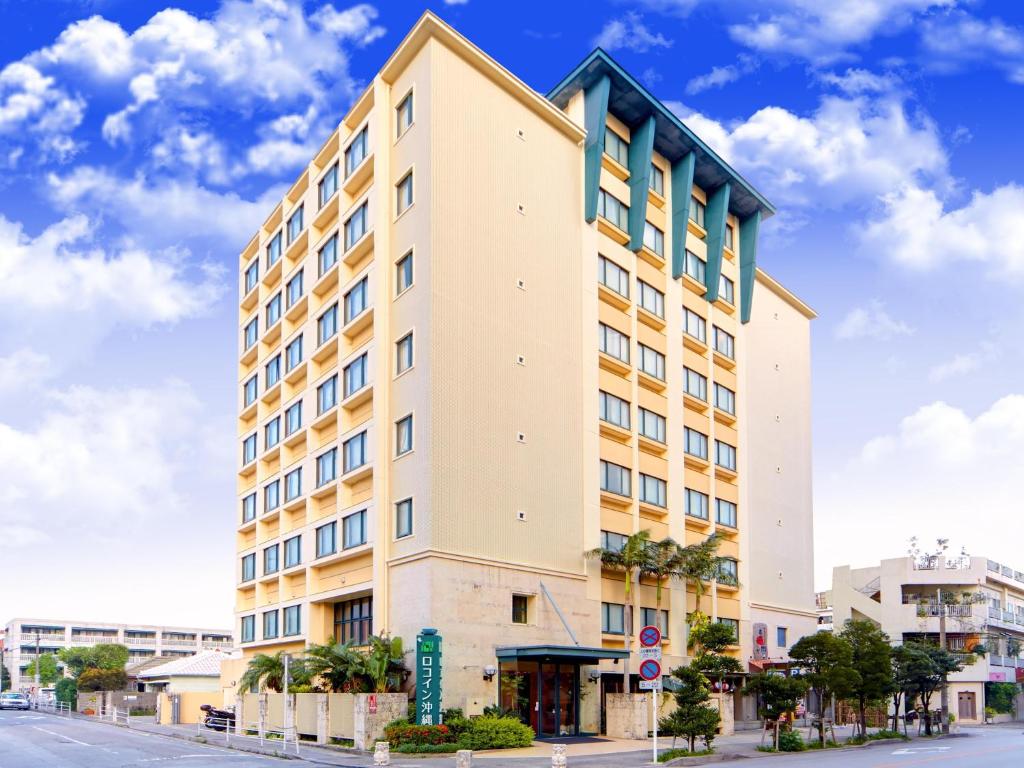 ein hohes weißes Gebäude in einer Stadtstraße in der Unterkunft Hotel Roco Inn Okinawa in Naha