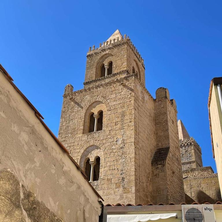 wysoki ceglany budynek z wieżą na górze w obiekcie Rocca&Torre Houses w Cefalù
