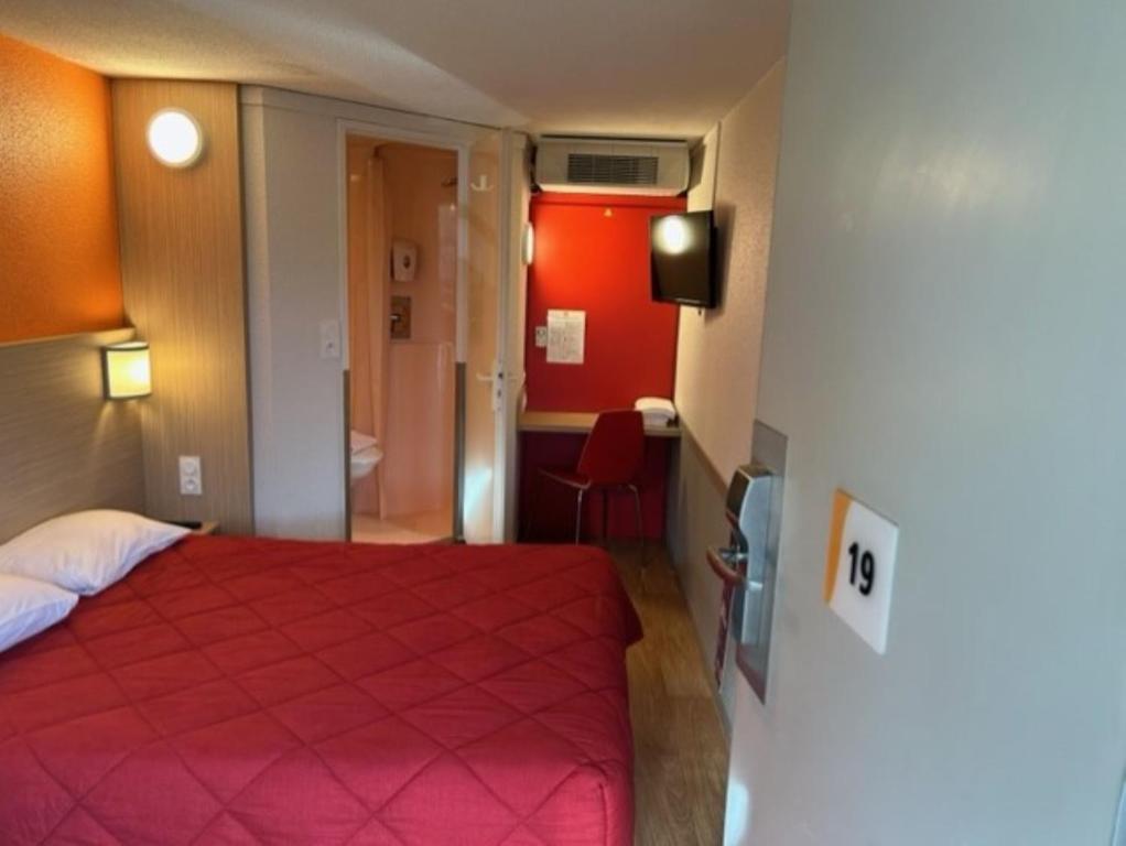 a hotel room with a red bed and a bathroom at Premiere Classe Blois Nord in Blois