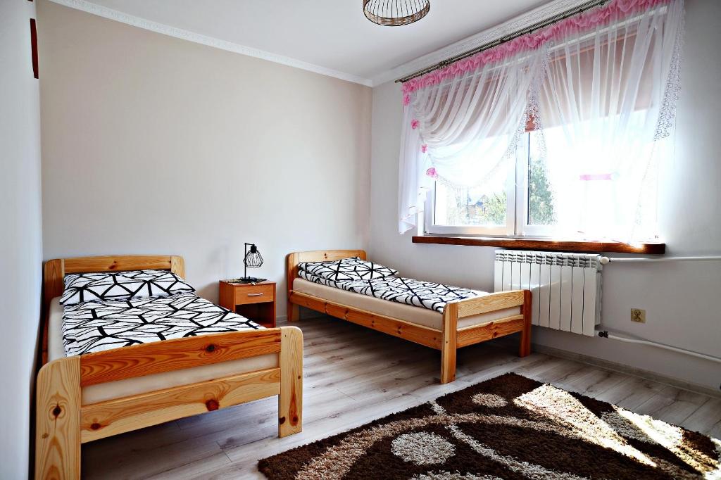 een slaapkamer met 2 bedden en een raam bij Apartamenty i Pokoje Gościnne nad Soliną Drozdówka in Solina