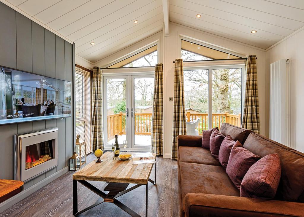 a living room with a couch and a fireplace at Wareham Forest Lodge Retreat in Lytchett Minster