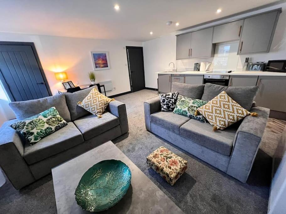a living room with two couches and a kitchen at Maxwell's Corner, Modern Coastal Apartment in North Shields