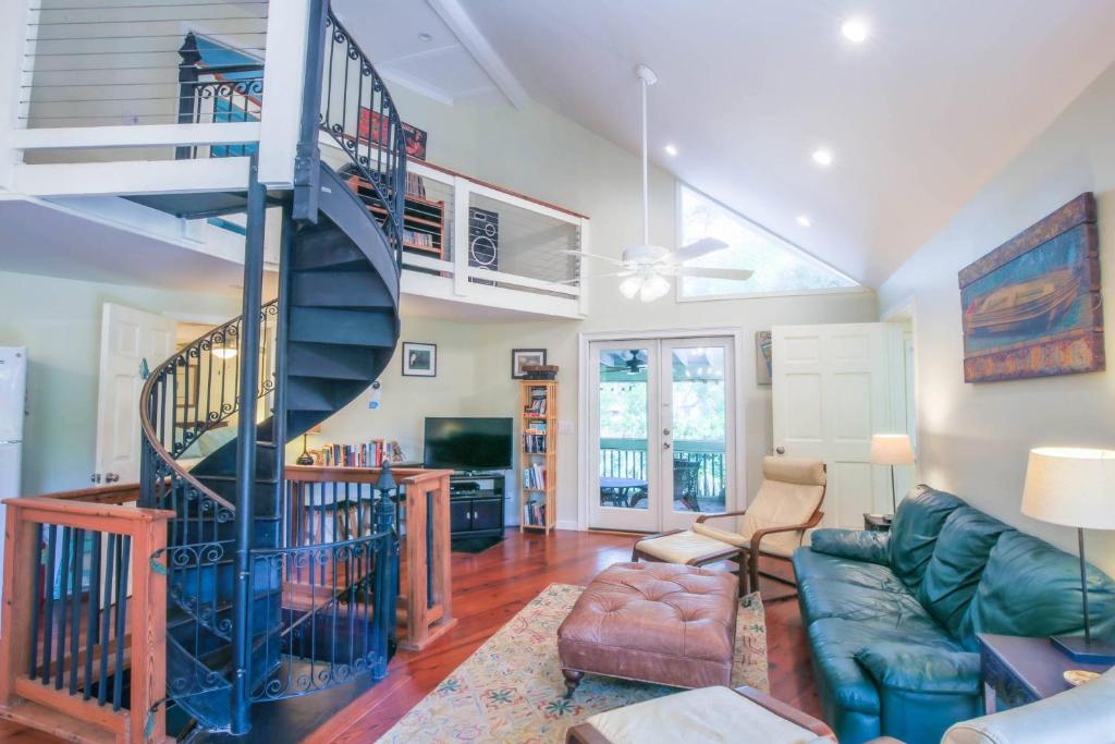 a living room with a blue spiral staircase at Shell Station House in Folly Beach