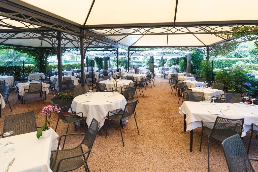 Hotel Ristorante Vecchia Riva في فاريزي: مجموعة من الطاولات والكراسي مع قماش الطاولة البيضاء