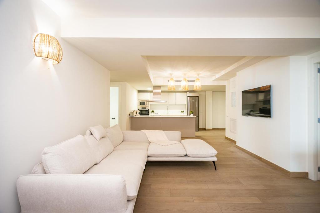 a living room with a white couch and a kitchen at Gran piso en Puerto deportivo Marina Palamós IDEAL FAMILIAS in Palamós