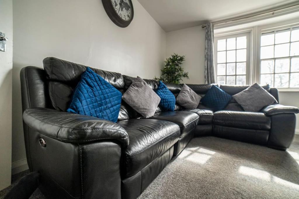 a black leather couch in a living room with a clock at Lovely flat in Crouch End in London