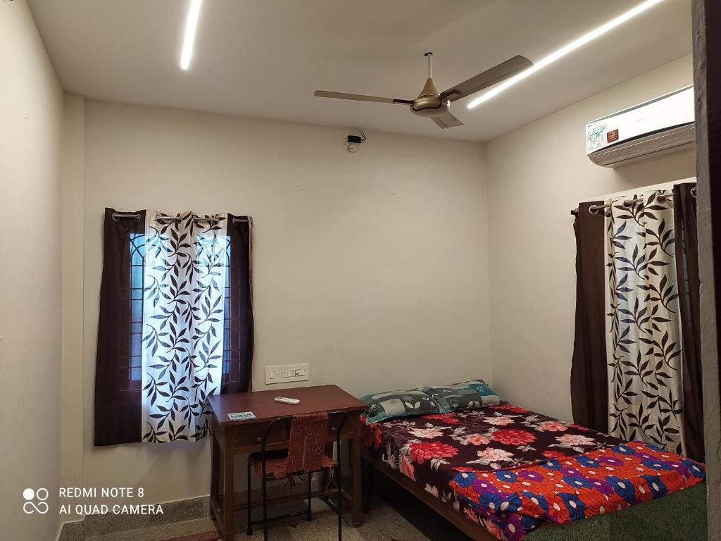 1 dormitorio con cama, mesa y ventana en Anve's Airport Nest, en Visakhapatnam