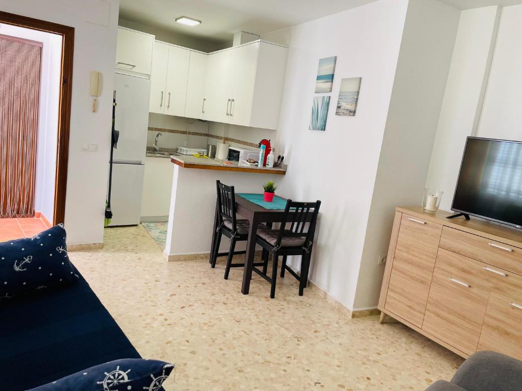 a living room with a table and chairs and a kitchen at Apartamento Conil Playa & Centro, perfecto descanso, con Aire Acond y WIFI in Conil de la Frontera