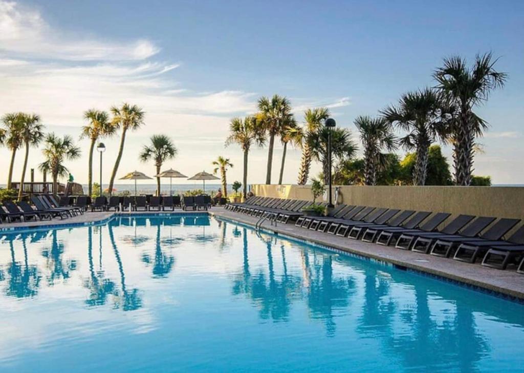 una grande piscina con sedie e palme di Beachfront, Spacious King Suite with Resort Access, Free Parking! a Myrtle Beach