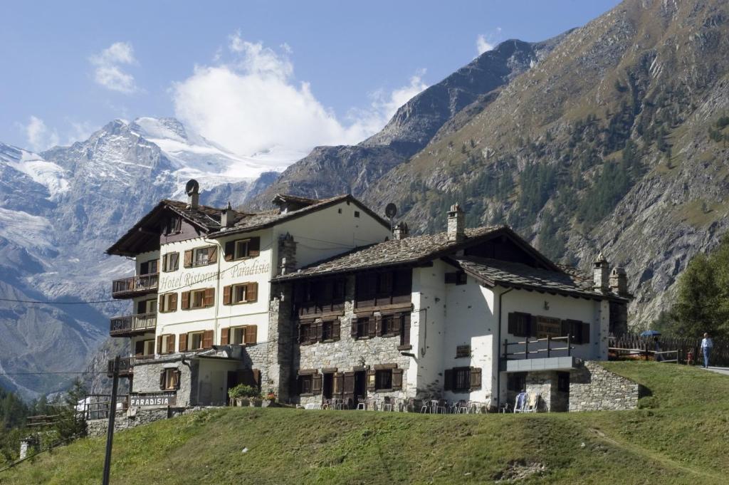 un bâtiment sur une colline avec des montagnes en arrière-plan dans l'établissement Lou Tsantelet, à Cogne