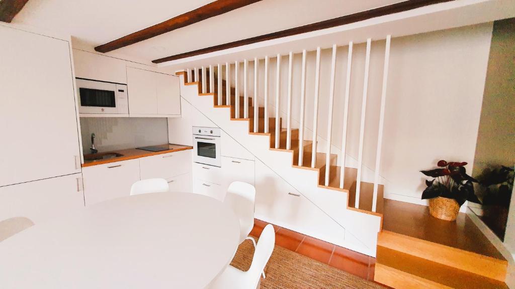 a white kitchen with a staircase in a house at Casa do Forno de Cal in Vila do Conde