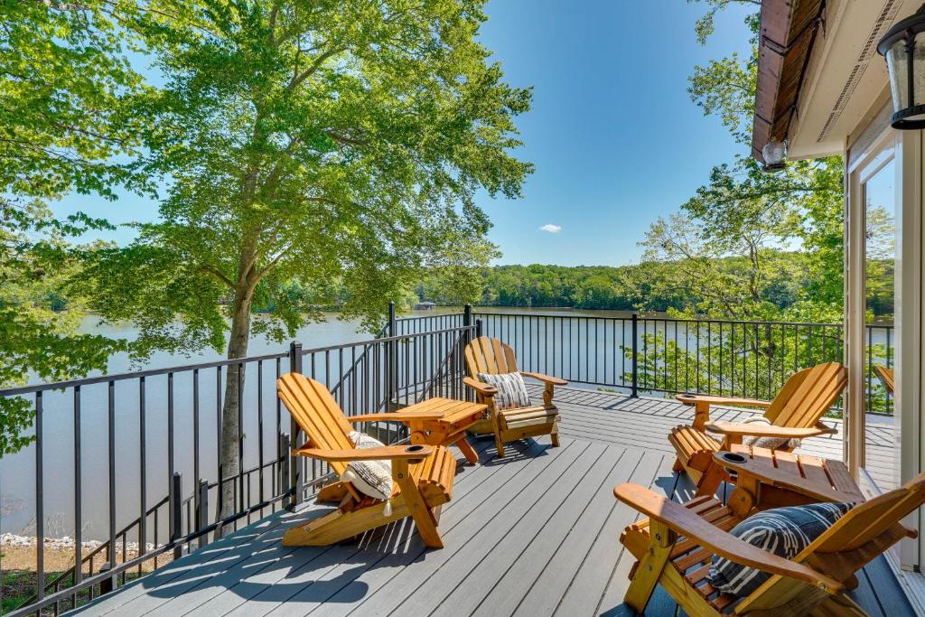 a deck with chairs and tables and a view of the water at Lakefront Vacation Rental with Views and Hot Tub! in Bracey