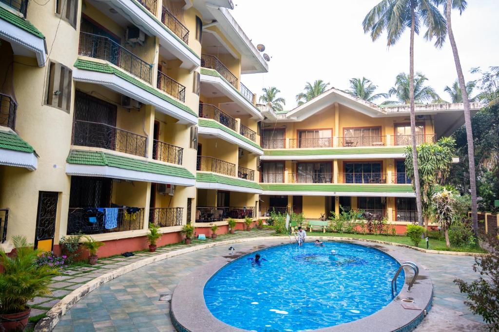 a hotel with a swimming pool in front of a building at Ronne's ZED Penthouse and apartment in Arpora